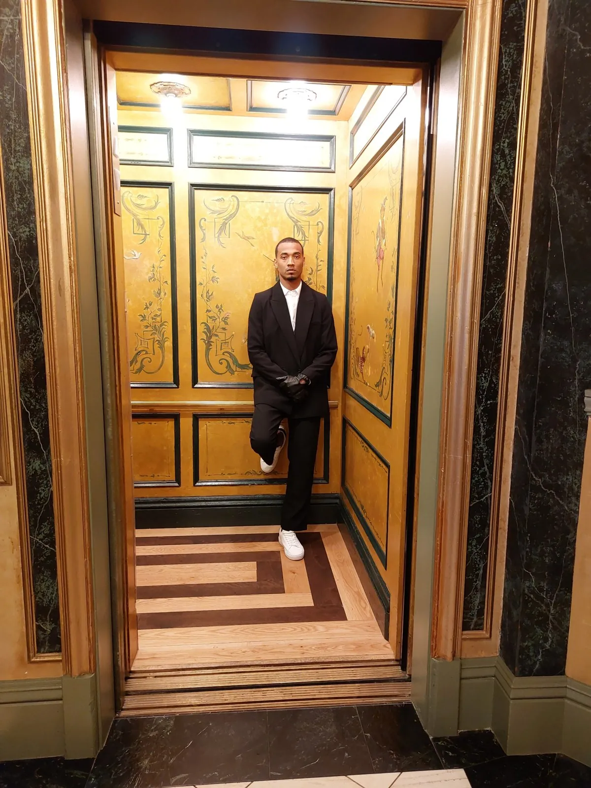 Vonté Smith — Black suit and leather gloves in an ornate elevator