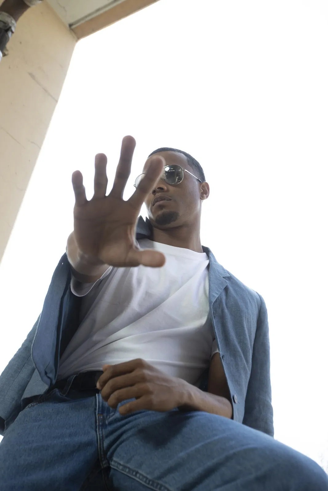Vonté Smith — Reaching toward the lens in sunglasses and denim
